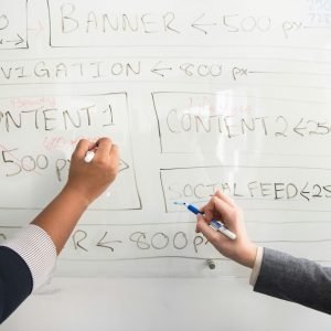 Two people collaboratively planning on a whiteboard with creative strategy.